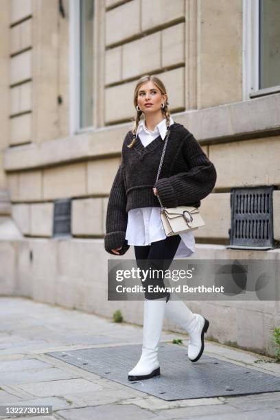 Xenia Adonts wears silver earrings, a pearls necklace, a white long oversized shirt from Attire The Studio, a dark gray woven wool oversized V-neck...