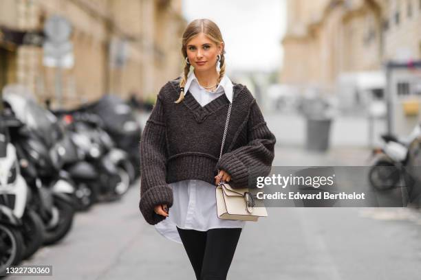 Xenia Adonts wears silver earrings, a pearls necklace, a white long oversized shirt from Attire The Studio, a dark gray woven wool oversized V-neck...