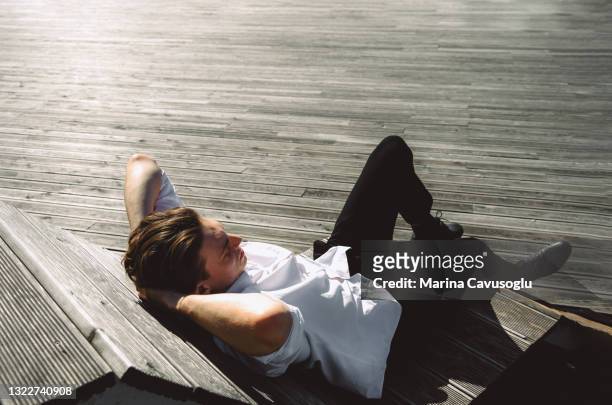young man enjoying summer sunny day in the city park wooden river embankment. - one embankment stock-fotos und bilder