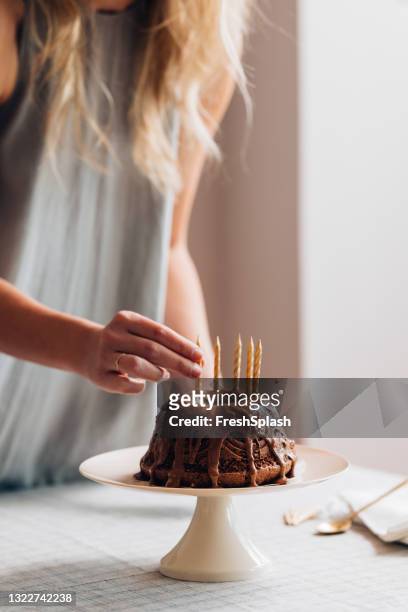 mujer colocando velas en un pastel de cumpleaños - pastel bundt fotografías e imágenes de stock