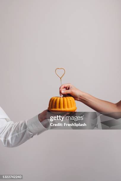 colocación de una vela en forma de corazón en un pastel, celebrando el concepto de amor - pastel bundt fotografías e imágenes de stock