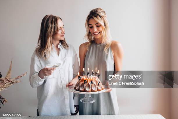 schwester liebe: zwei lächelnde frauen feiern gemeinsam geburtstag - geburtstagstorte stock-fotos und bilder