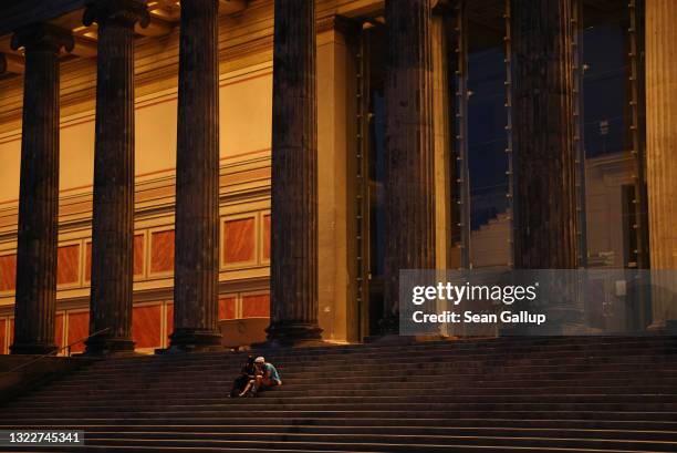 Couple relax on a warm summer evening on the steps of the Altes Museum during the coronavirus pandemic on June 09, 2021 in Berlin, Germany....