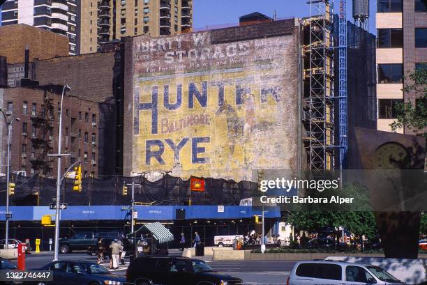 View of advertisements visible on a previously covered wall behind a construction site at the intersection of Broadway and Lincoln Plaza , New York,...