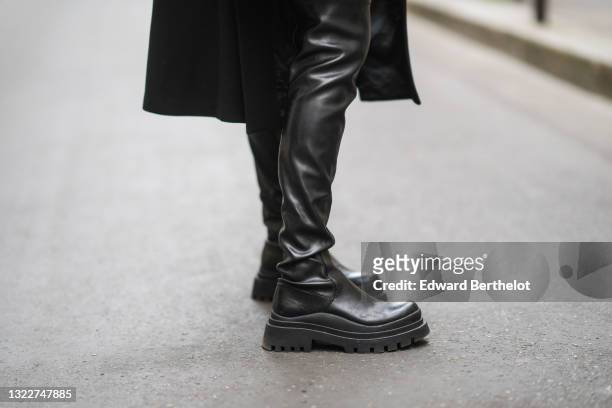 Almuneda Lapique wears a long black Prada coat, black shiny leather Prada waders boots, on May 12, 2021 in Paris, France.