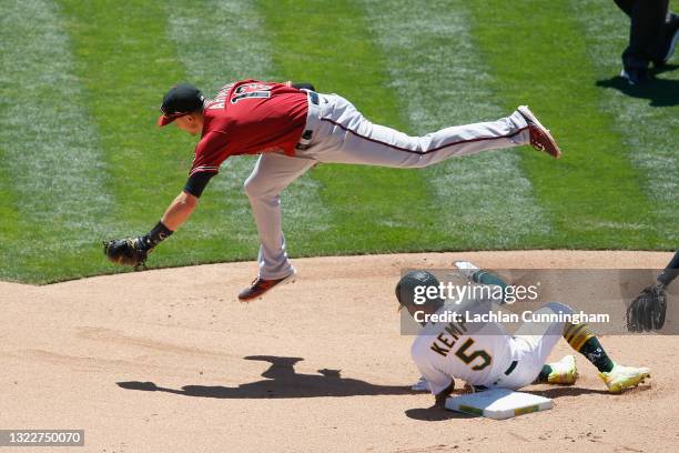 Nick Ahmed of the Arizona Diamondbacks jumps over Tony Kemp of the Oakland Athletics after getting him out at second base and turning a double play...