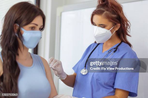 nurse preps patient prior to covid-19 injection - nursing scrubs stock pictures, royalty-free photos & images