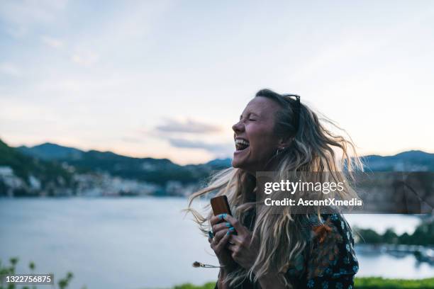 jonge vrouwenteksten op cellphone van lakefront gezichtspunt - sober leven stockfoto's en -beelden
