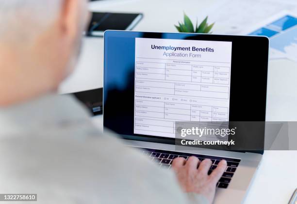 mature man filling out an online unemployment benefits application form. - unemployment benefits stock pictures, royalty-free photos & images