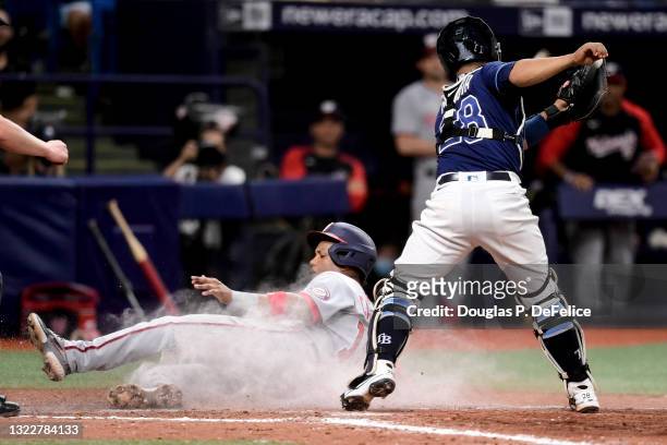 Starlin Castro of the Washington Nationals slides safely into home plate under the glove of Francisco Mejia of the Tampa Bay Rays on an sacrifice fly...