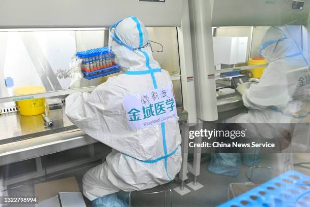 Medical worker wearing personal protective equipment works in a mobile COVID-19 testing laboratory at Baiyun International Airport on June 9, 2021 in...