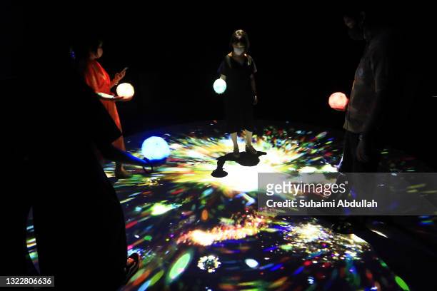 People interact with an exhibit titled, Rezonance 2021, by Enhance and Rhizomatiks during a media preview for 'Virtual Realms: Videogames...