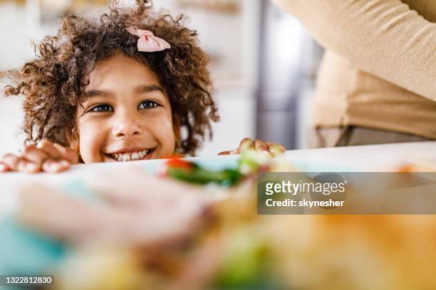 cute african american girl peeking behind dining table. - kid peeking stock pictures, royalty-free photos & images