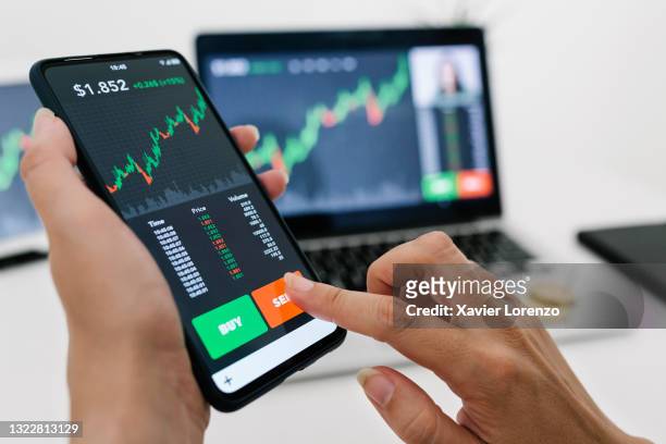 businesswoman selling cryptocurrencies through a mobile app - koersinformatie stockfoto's en -beelden