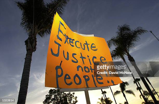 Protester holds a sign up against a backdrop of palm trees during an anti-death penalty protest on the eve of the second federal execution in nearly...