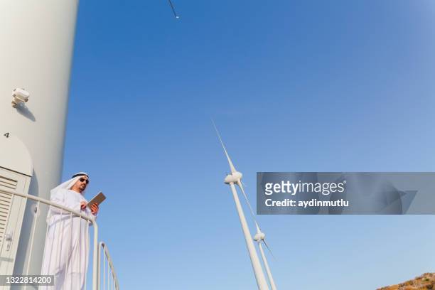 empresario árabe trabajando con tableta digital en aerogeneradores - gulf countries fotografías e imágenes de stock