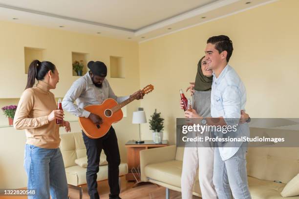 foto einer close group of good friends who is dancing together and listening to a african friend playing the guitar. - we love latinos latin thespians stock-fotos und bilder