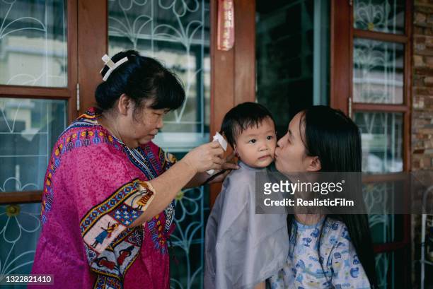 grandmother giving her grandson haircut at home - glamourous granny stockfoto's en -beelden