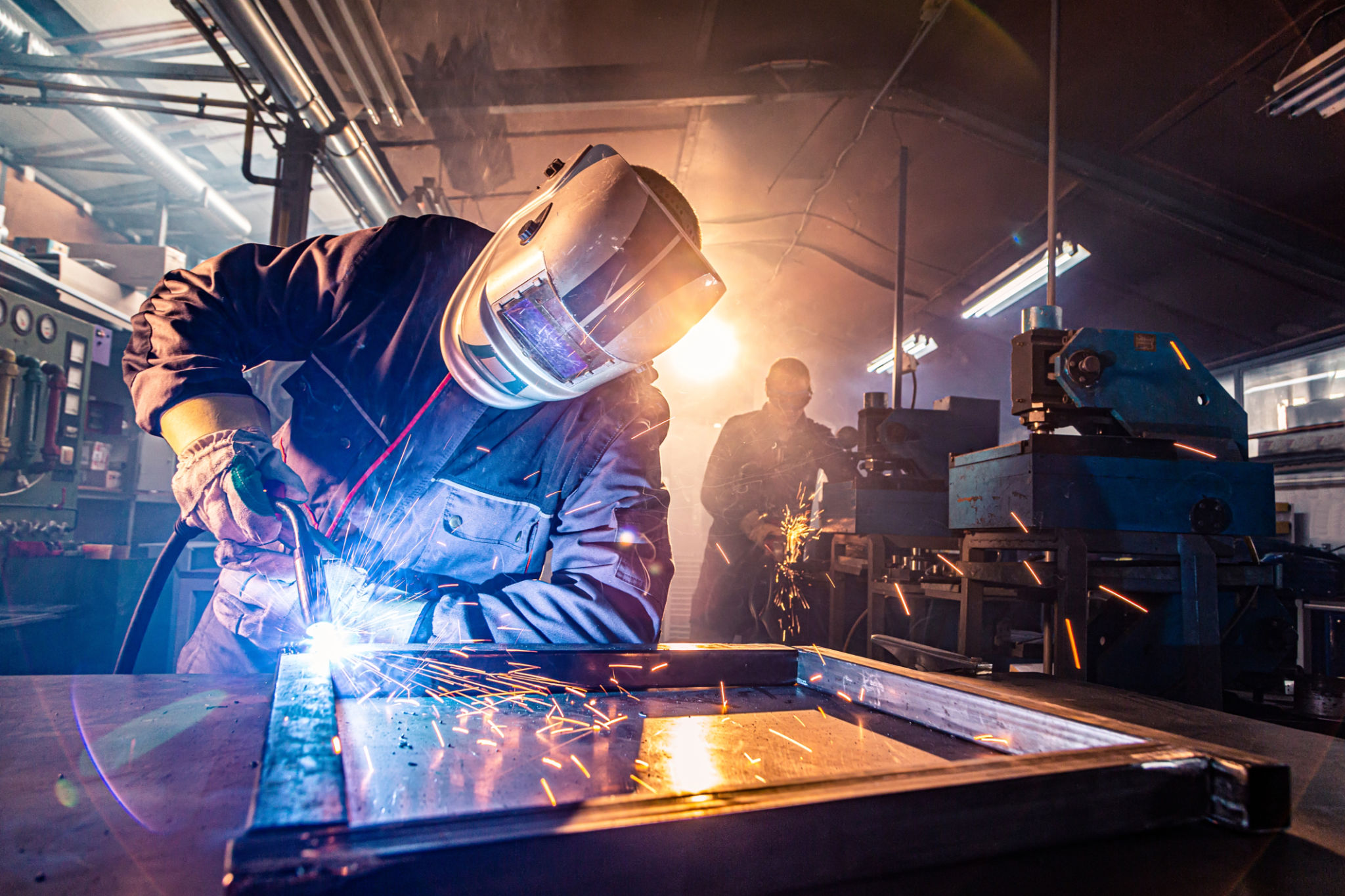Two handymen welding and grinding metal at workshop Two handymen welding and grinding metal at workshop
