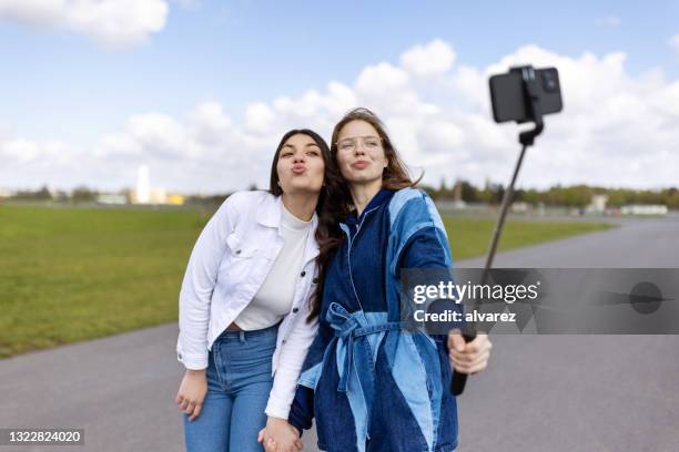 beautiful women standing on tempelhof airstrip taking selfie - puckering stock pictures, royalty-free photos & images