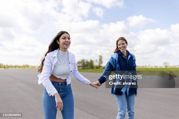 female friends skating together holding hands - tempelhof airport stock pictures, royalty-free photos & images