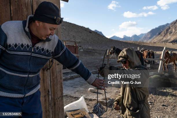 Kuban, left, a conservationist, receives a camera trap from a ranger as he return to the cabin at Sarychat-Ertash State Nature Reserve on May 21,...