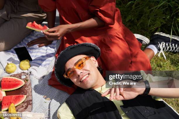 man relaxing with a group of friends enjoying a picnic - piquenique imagens e fotografias de stock