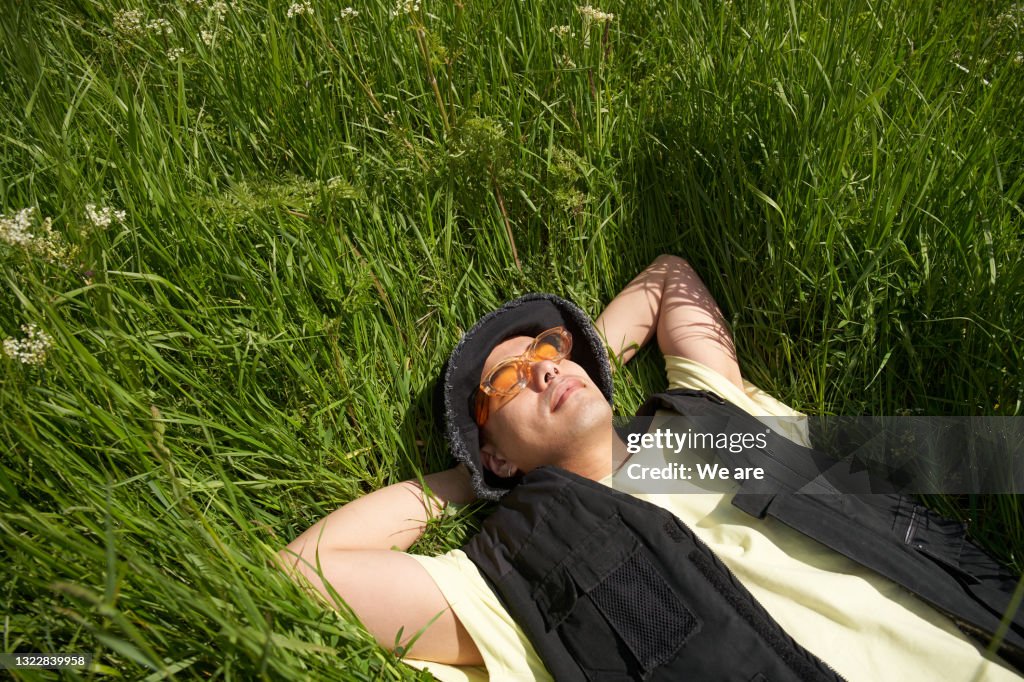 Man lying back in long grass enjoying the sunshine
