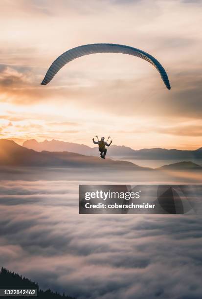 man paragliding above the clouds at sunset, salzburg, austria - paragliding stockfoto's en -beelden