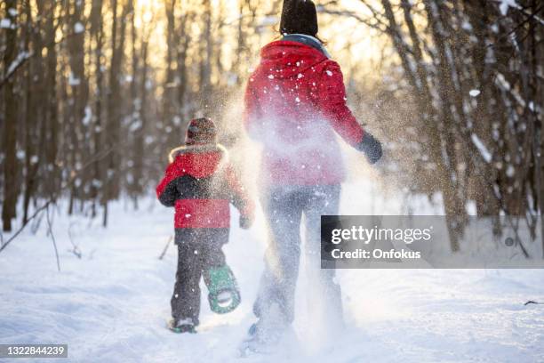 mother and son running with snowshoes in powder snow outdoors in winter during sunset - quebec icy trail stock pictures, royalty-free photos & images