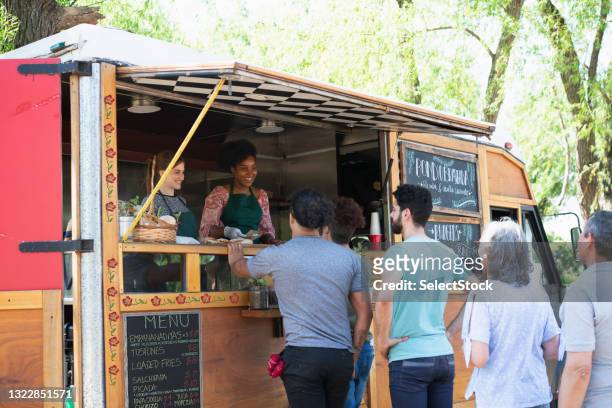 people making line to buy food from food truck - foodtruck stockfoto's en -beelden