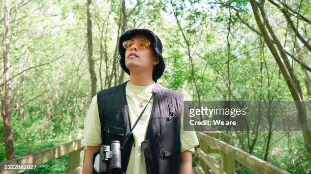 young man on a nature walk in woodland - binoculars woods stock-fotos und bilder