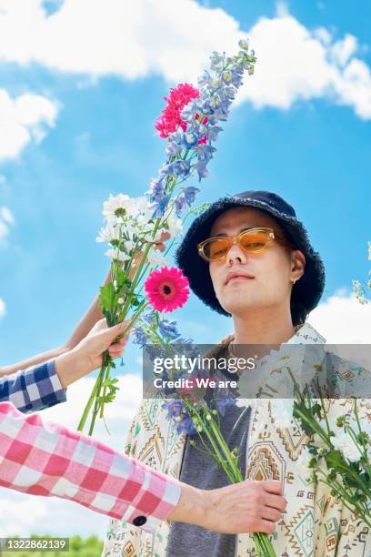 fashionable man poses with flowers - holding sunglasses stockfoto's en -beelden
