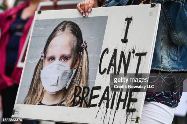 Close-up of a protest sign showing a young girl wearing a mask during an anti-mask rally in Kings Park, New York on June 8, 2021. The sign reads, "I...
