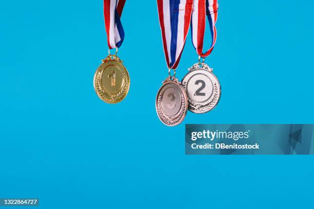 three sports competition winner medals hanging on blue background - championship round three stockfoto's en -beelden