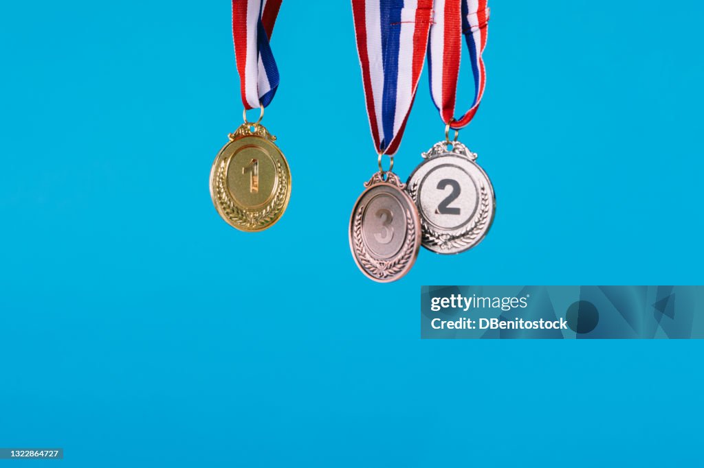 Three sports competition winner medals hanging on blue background