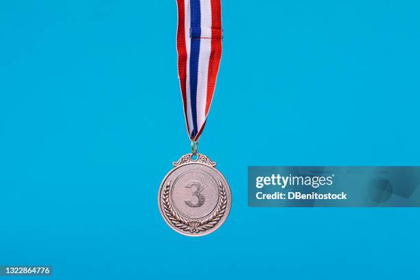 third place bronze medal of sports competition hanging, on blue background - third place ribbon stock pictures, royalty-free photos & images