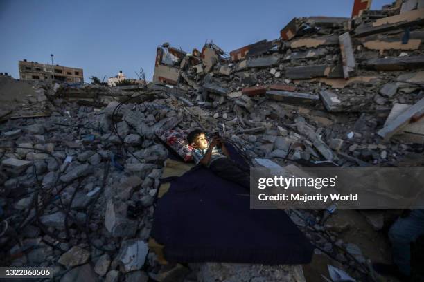 Palestinian child plays with a mobile device on the rubble of his house, which was destroyed by Israeli aircraft during the recent attacks. Gaza City.