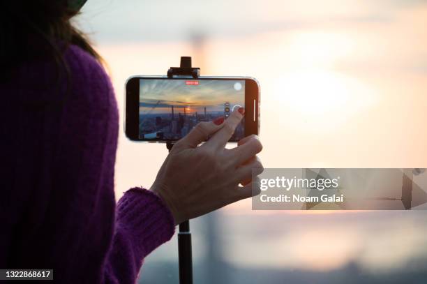 Person records a video of the sun as it rises over New York City during a solar eclipse on June 10, 2021 as seen from The Edge observatory deck at...