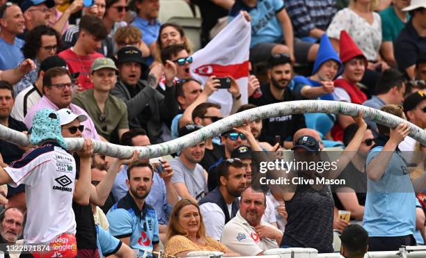 Spectators enjoy themselves with the construction of a beer snake in the Hollies stand during day one of the second Test Match between England and...