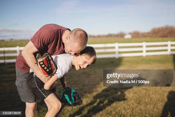 father and son laughing,playing outside,playing catch in the field,st charles,missouri,united states,usa - playing catch stock pictures, royalty-free photos & images