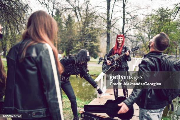 friends putting cash in female busker's guitar case during park performance - street musician stock pictures, royalty-free photos & images