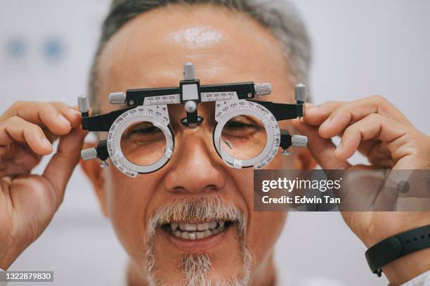 paciente chino asiático del hombre mayor que comprueba la vista en clínica oftalmológica - miope and humor fotografías e imágenes de stock