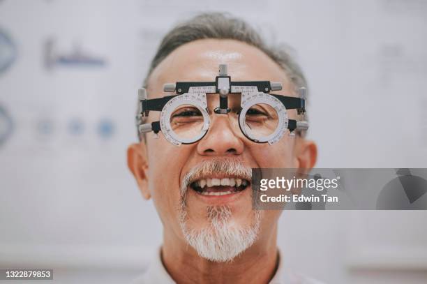 asian chinese senior man patient checking eyesight in ophthalmological clinic - phoropter stock pictures, royalty-free photos & images