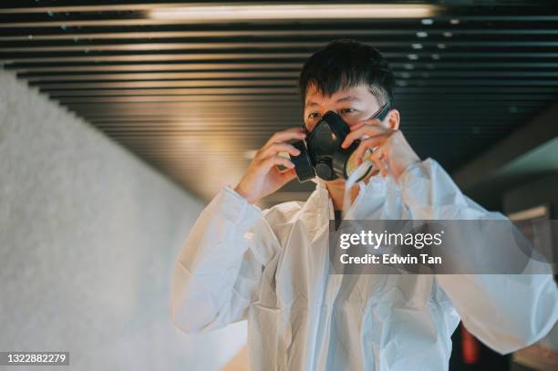 asiatische chinesische kinoreiniger arbeiter tragen und setzen auf atemmaske schutzarbeitskleidung durchführung desinfektion in kino laufsteg vor der filmshow zeit - atemschutz stock-fotos und bilder