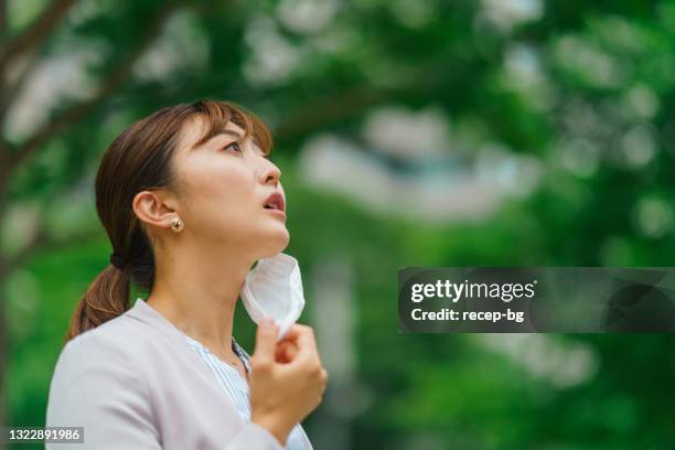 businesswoman removing protective face mask from her face and taking deep breath to relax - protective face mask side stock pictures, royalty-free photos & images