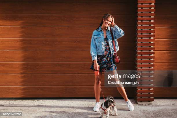 happy woman walking a dog on a leash in the city street - happy lady walking dog stockfoto's en -beelden