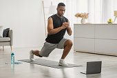 Black Guy Doing Forward Lunge Exercise At Laptop At Home