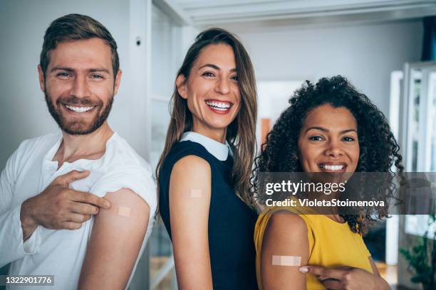 amigos mostrando sus brazos después de vacunarse. - vacuna fotografías e imágenes de stock