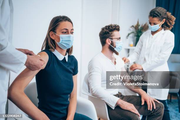 young couple getting vaccinated together. - vaccination center stock pictures, royalty-free photos & images